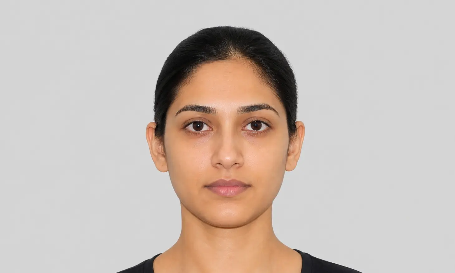 Evenly lit UK passport portrait with hair pulled back so the ears are visible and the face has no shadow